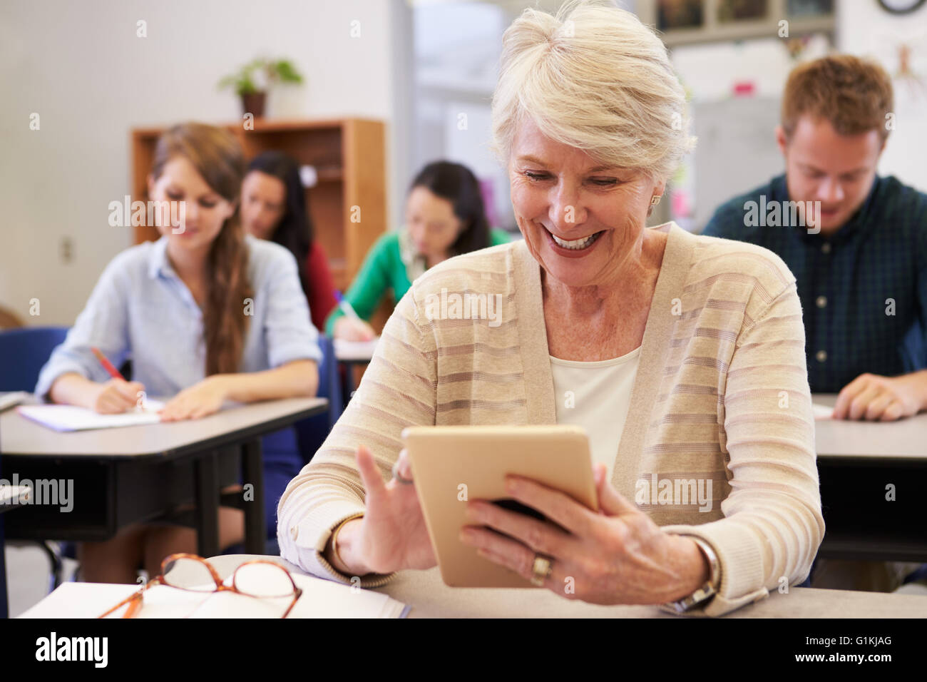 Senior donna utilizzando computer tablet all educazione degli adulti di classe Foto Stock