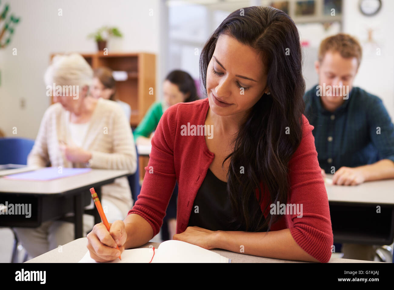Donna ispanica a studiare in un'istruzione per adulti della classe Foto Stock