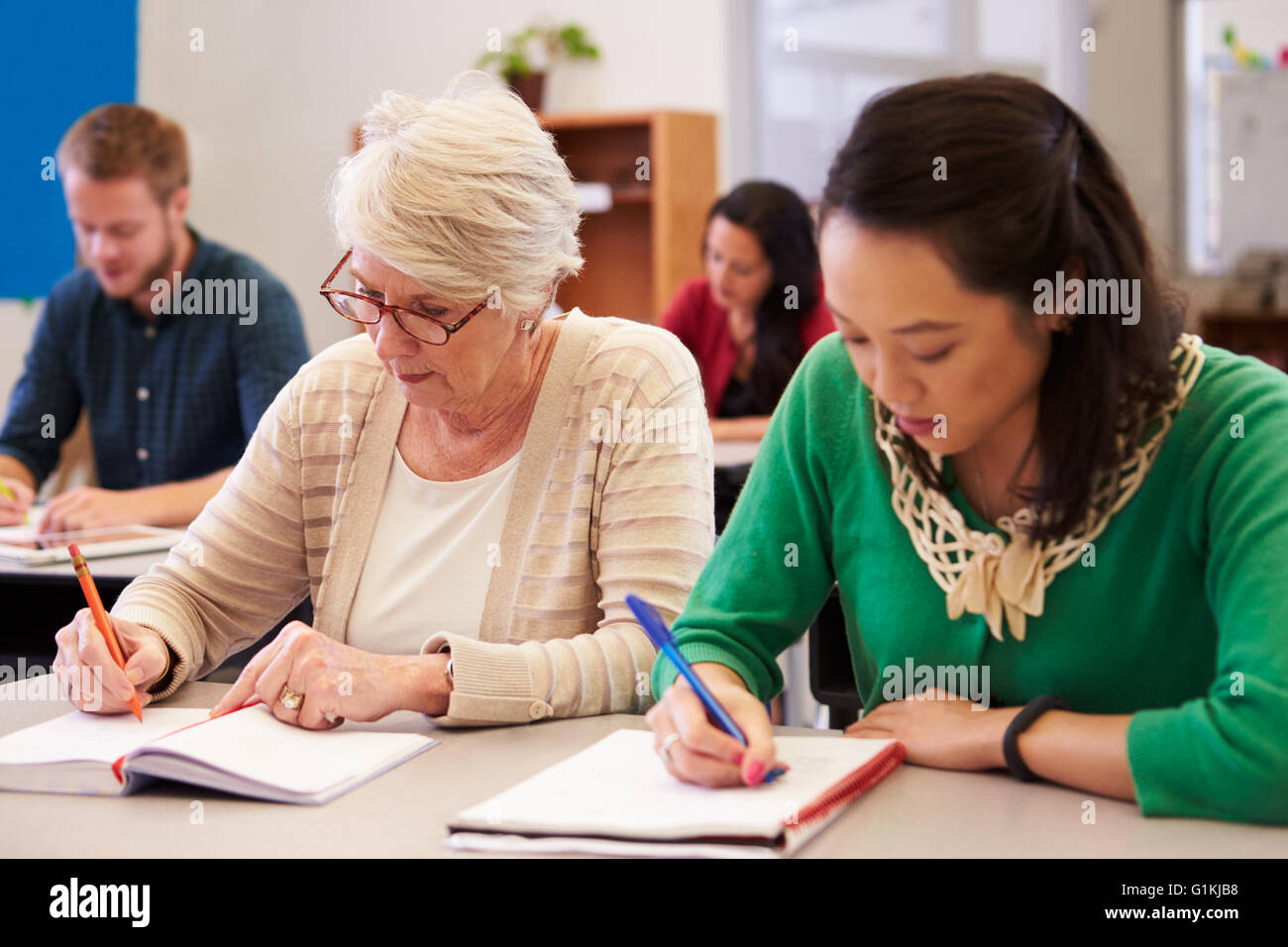 Due donne che condividono un banco in un adulto istruzione class Foto Stock