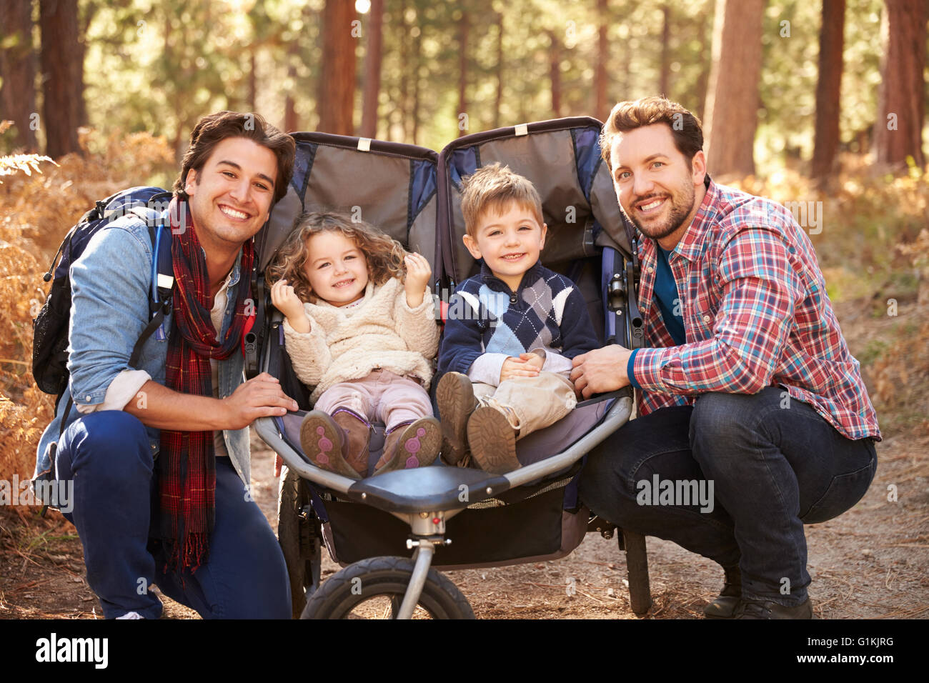 Gay maschio giovane spingendo i bambini in Buggy attraverso boschi Foto Stock