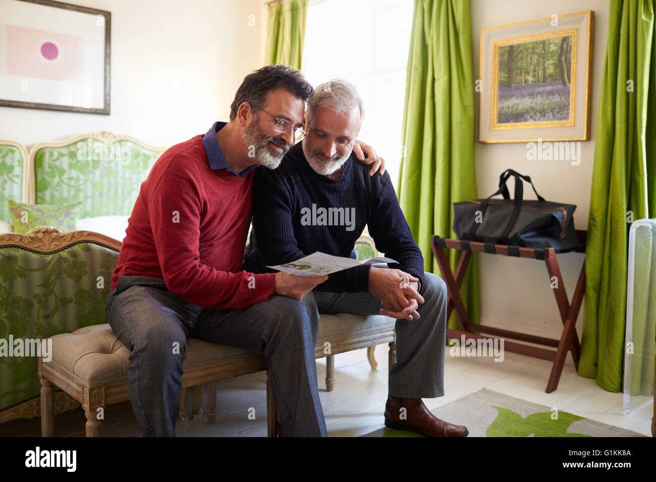 Voce maschile giovane la lettura di una brochure di guida nella loro camera di albergo Foto Stock