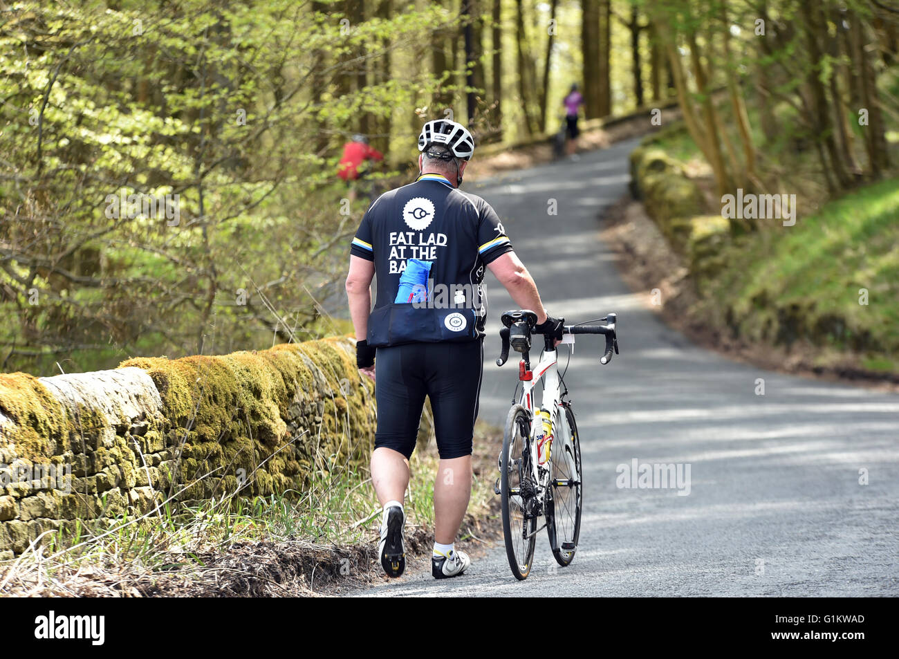 Il sovrappeso ciclista a piedi la sua bici fino alla cima di una collina su un sportivi, Yorkshire Foto Stock
