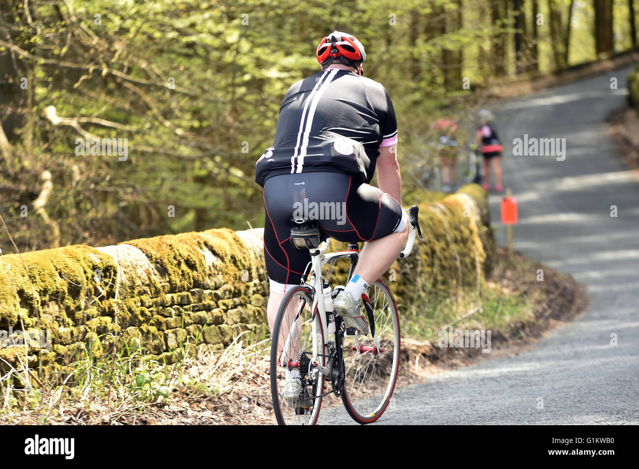 Uomo sovrappeso ciclista in sella fino alla cima di una collina su un sportivi, Yorkshire Foto Stock