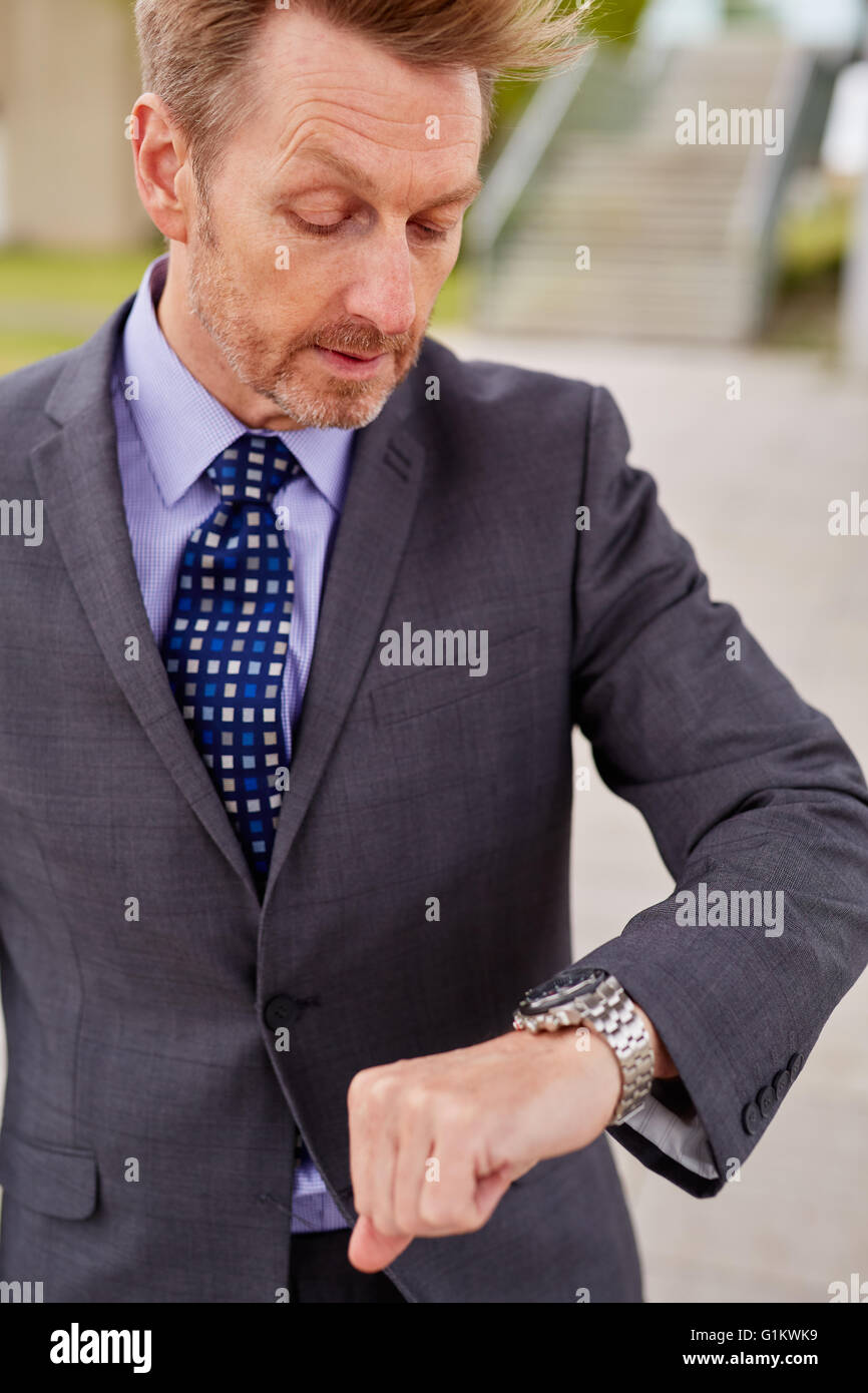 Uomo che guarda il suo orologio correndo per il lavoro Foto Stock