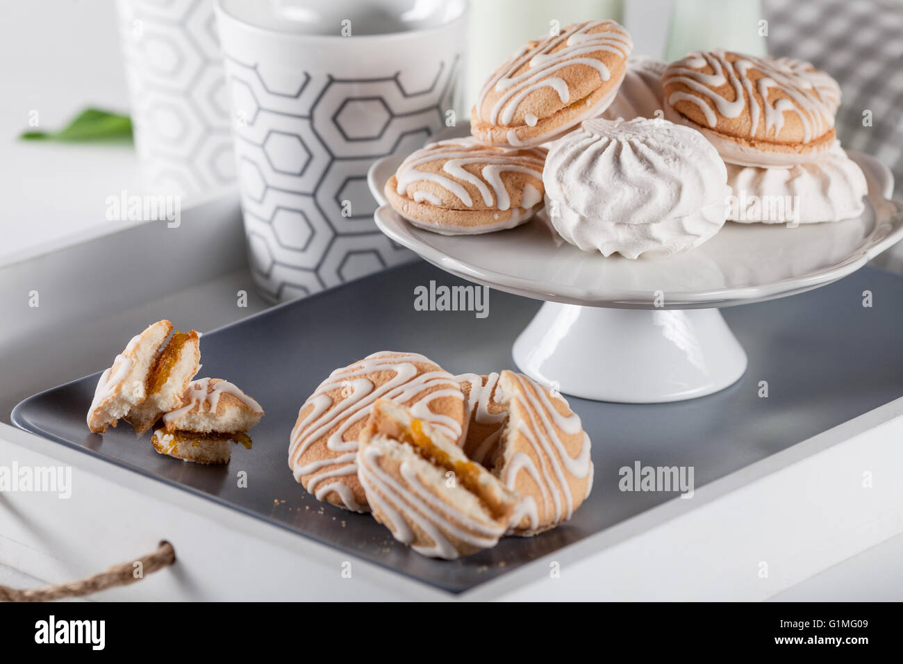 I cookie su bianco e grigio con piastra di tazze di caffè e bottiglie di latte bianco su sfondo serrande Foto Stock