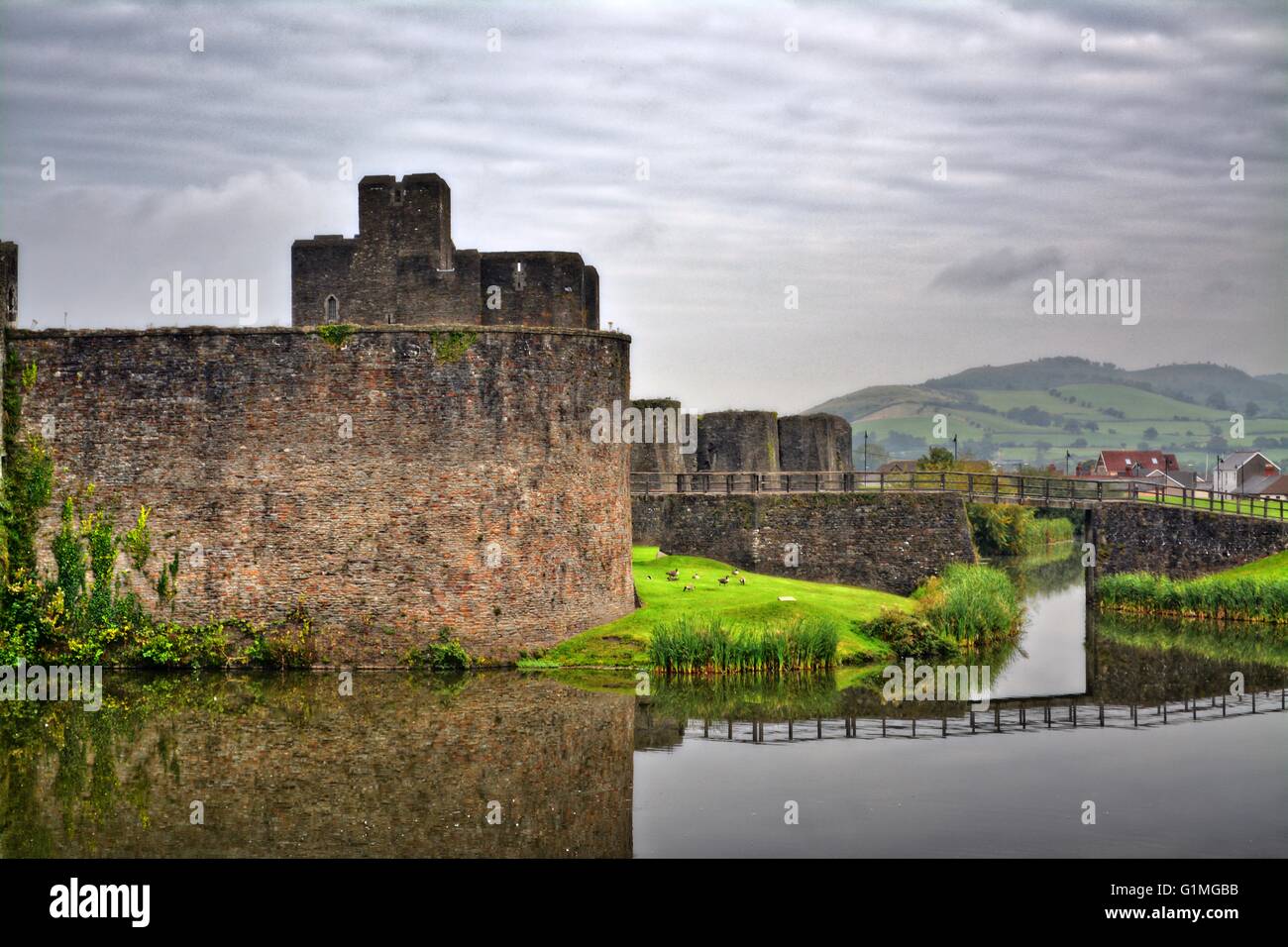 Vista Kidwelly Castle, Gallese montagne acqua riflettente e un cielo nuvoloso Foto Stock