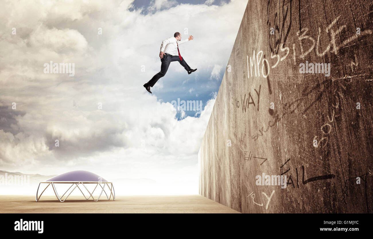 Imprenditore saltare su di una parete di cemento Foto Stock