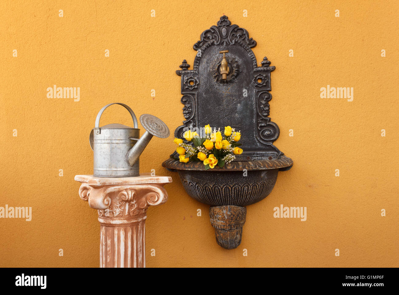 Ghisa fontana a muro affiancato da un greco colonna ionica sopra con un annaffiatoio all'acqua di rose Foto Stock