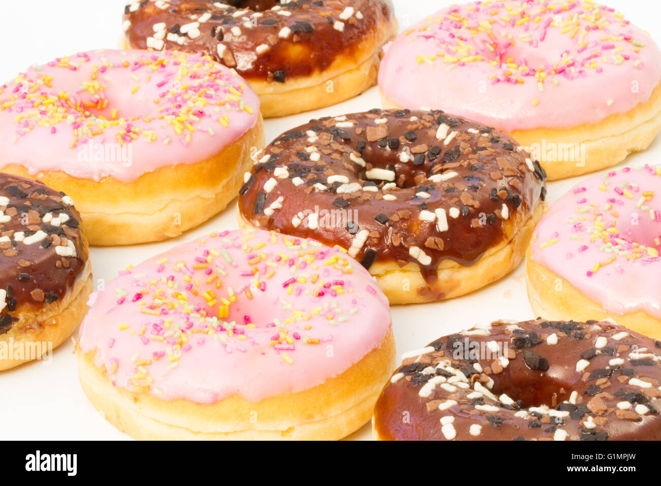 Righe di cioccolato e rosa ciambelle glassate con spruzzino isolato su un fondo bianco. Foto Stock