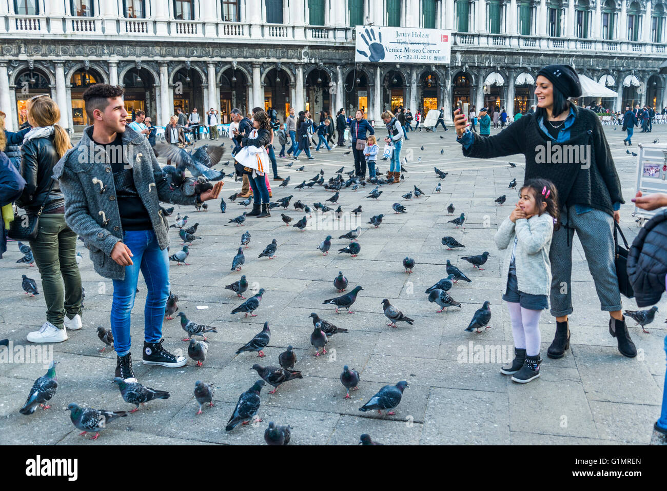 I turisti a scattare foto di ogni altro con pigeaons su Piazza San Marco, Venezia Foto Stock
