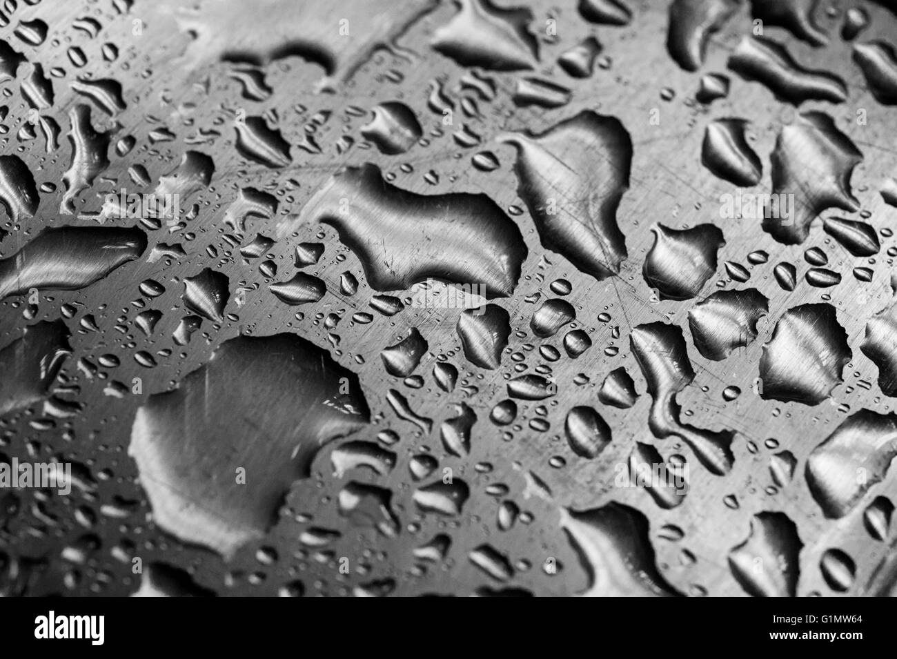 Gocce d'acqua sulla graffiato in acciaio inox Foto Stock