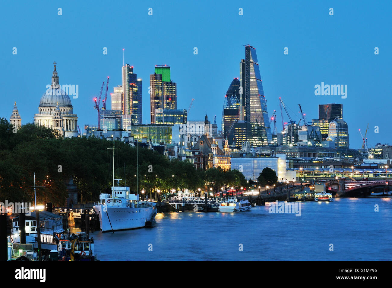 Skyline della citta' di Londra, dal Ponte di Waterloo, con gli edifici degli uffici della citta' e la cupola della Cattedrale di St Paul, illuminata in prima serata Foto Stock