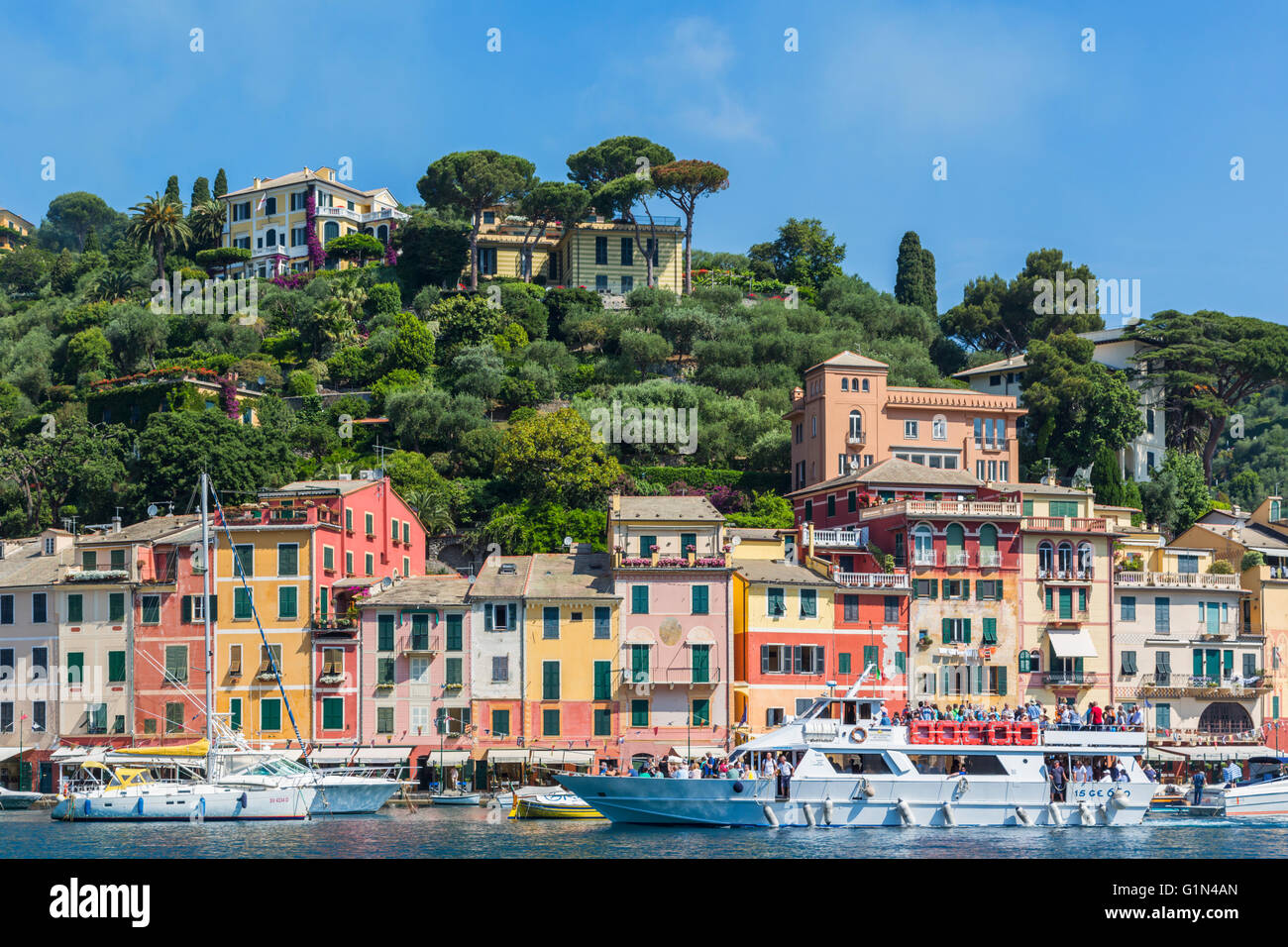 Portofino, la provincia di Genova, Liguria, Riviera Ligure, Italia. Le barche nel porto con il villaggio dietro. Foto Stock
