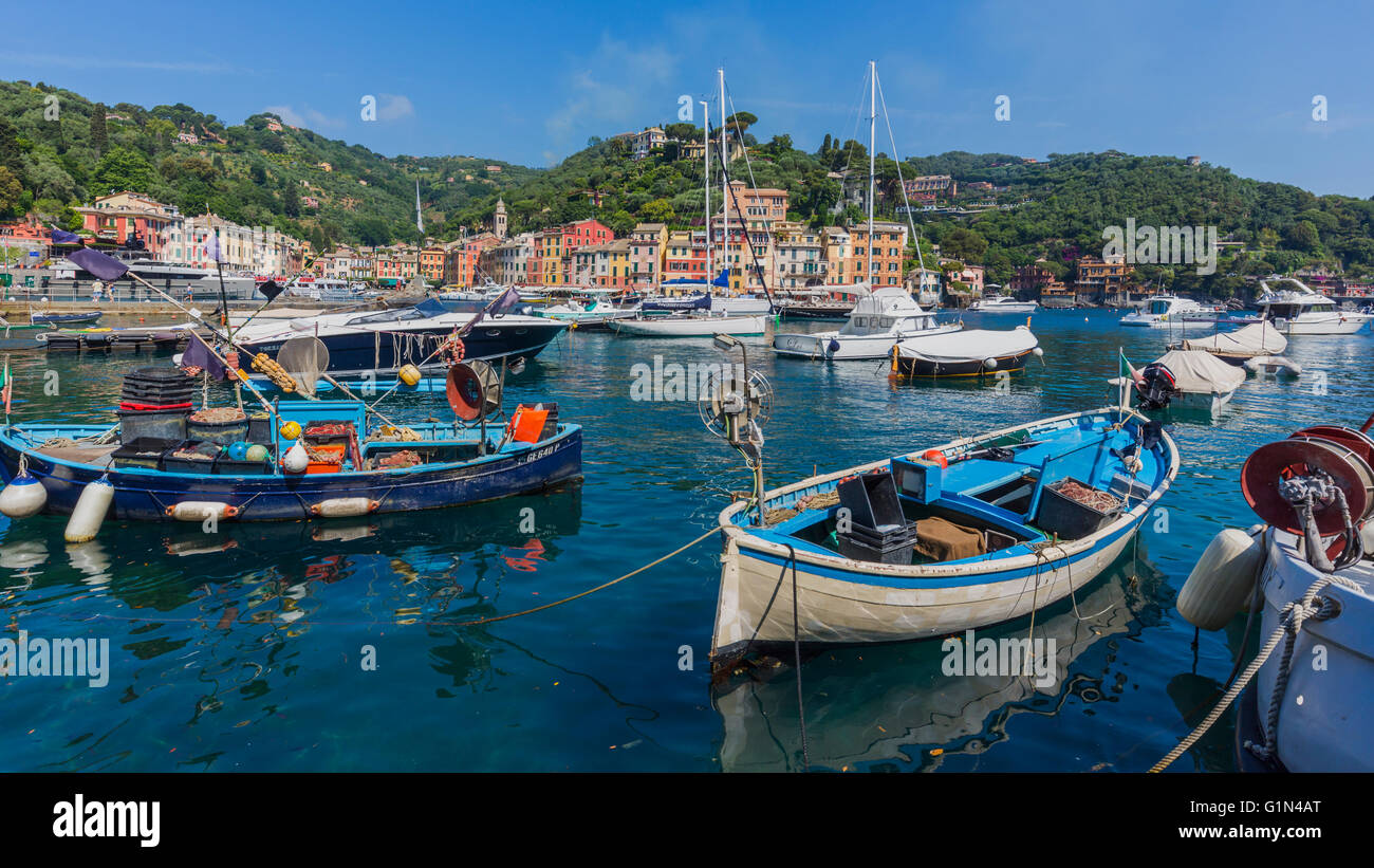 Portofino, la provincia di Genova, Liguria, Riviera Ligure, Italia. Le barche nel porto con il villaggio dietro. Foto Stock