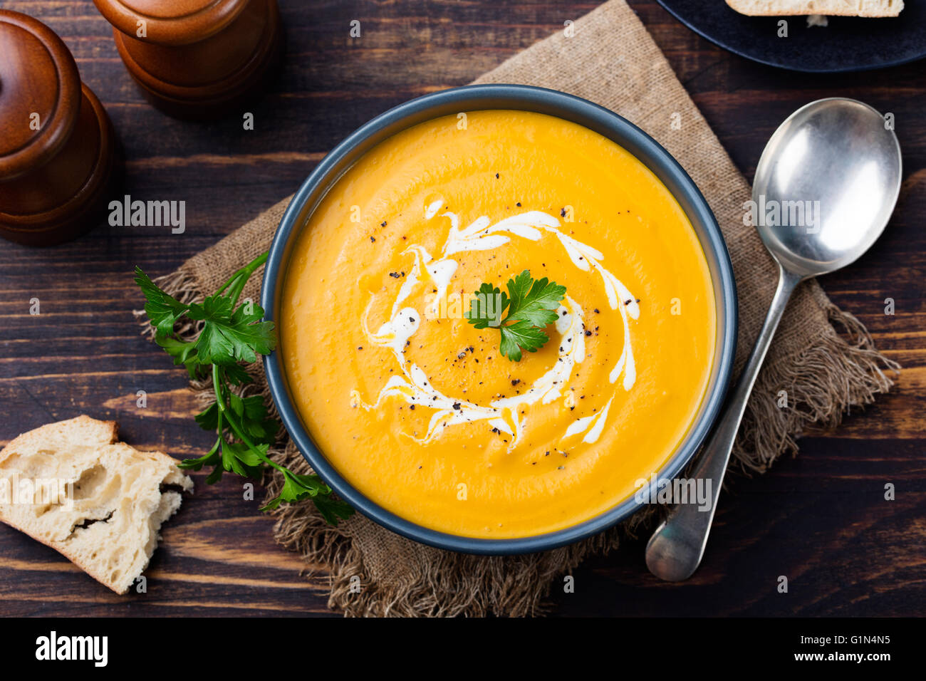 Zucca e carote zuppa con la panna e il prezzemolo sul legno scuro dello sfondo vista superiore. Foto Stock