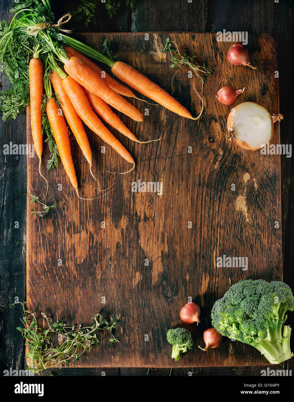 Legno alimenti sani sfondo con verdure crude e erbe aromatiche. Carote, cipolle, broccoli e timo in legno superficie testurizzata. Foto Stock