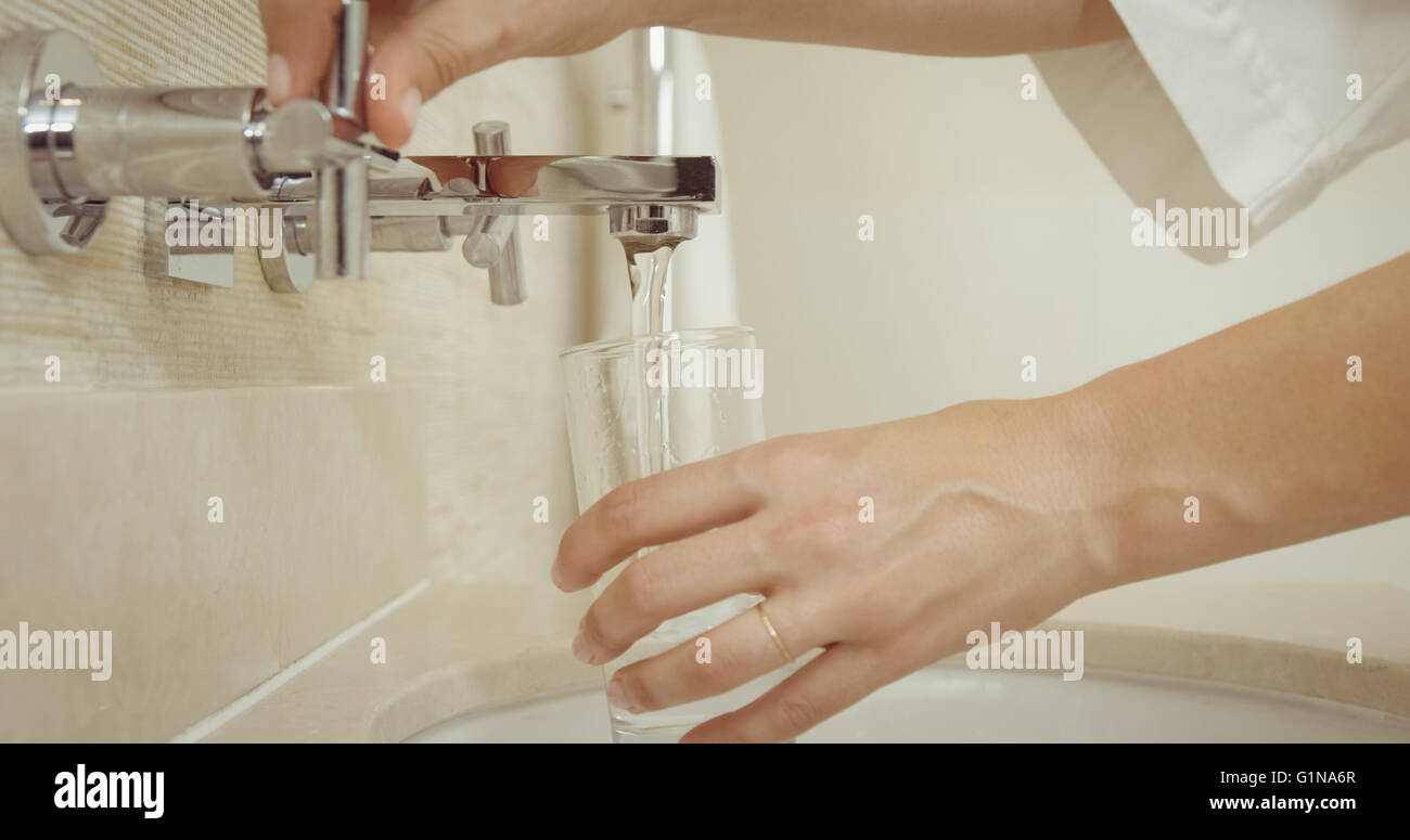 Donna prendendo l'acqua del rubinetto Foto Stock