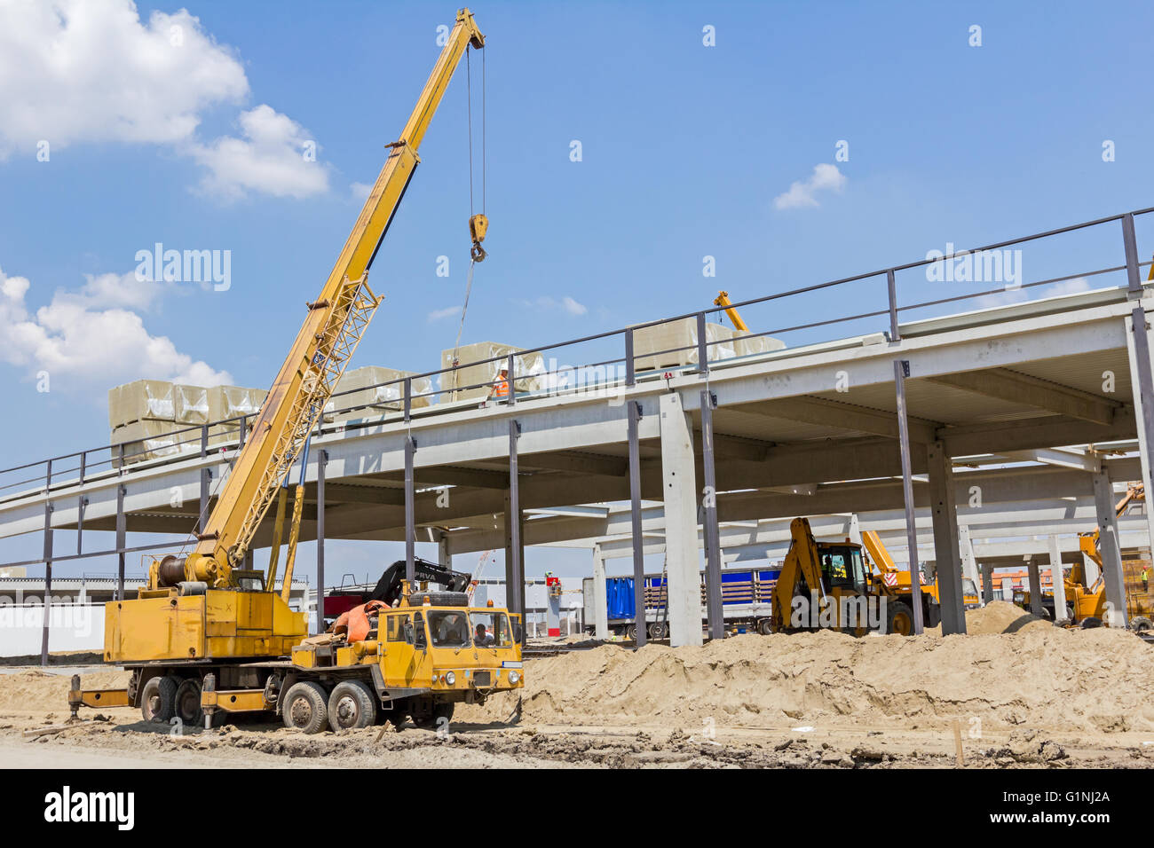 Gru mobile è in fase di caricamento del carico. Vista sul sito di costruzione di macchinari, la gente al lavoro. Foto Stock