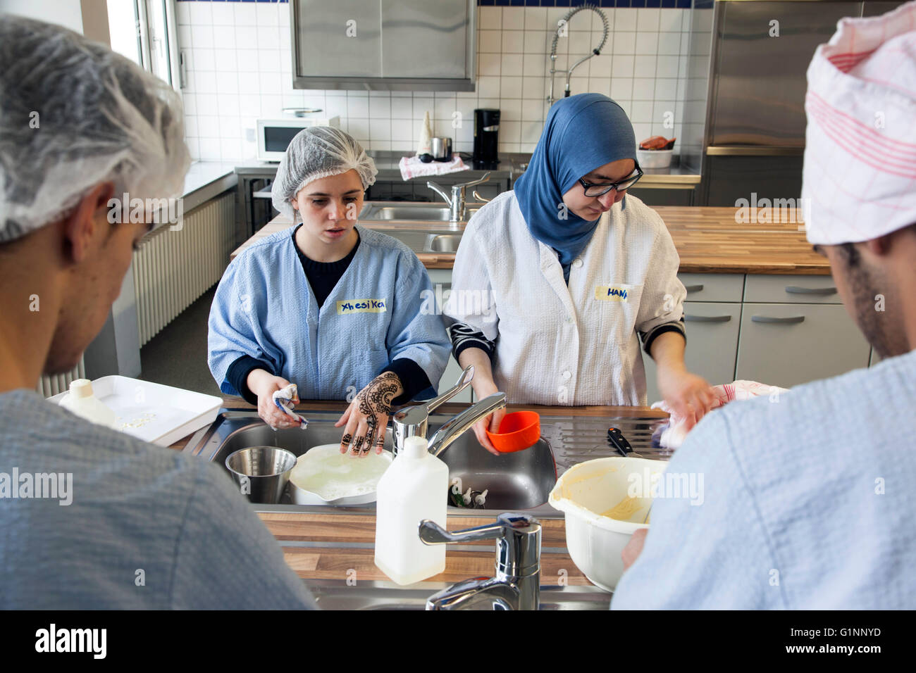 Classe internazionale durante la cottura di una torta a scuola di cucina. I tirocinanti lavare gli utensili da cucina. Foto Stock