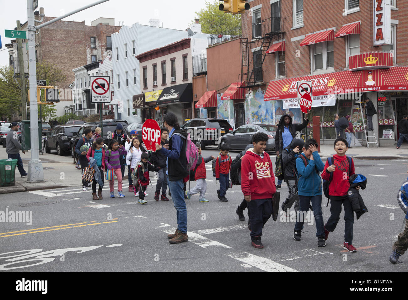 Gli insegnanti utilizzano segni di arresto per il traffico come scuola i bambini in un itinerario attraversa una grande Street in Brooklyn, New York. Foto Stock