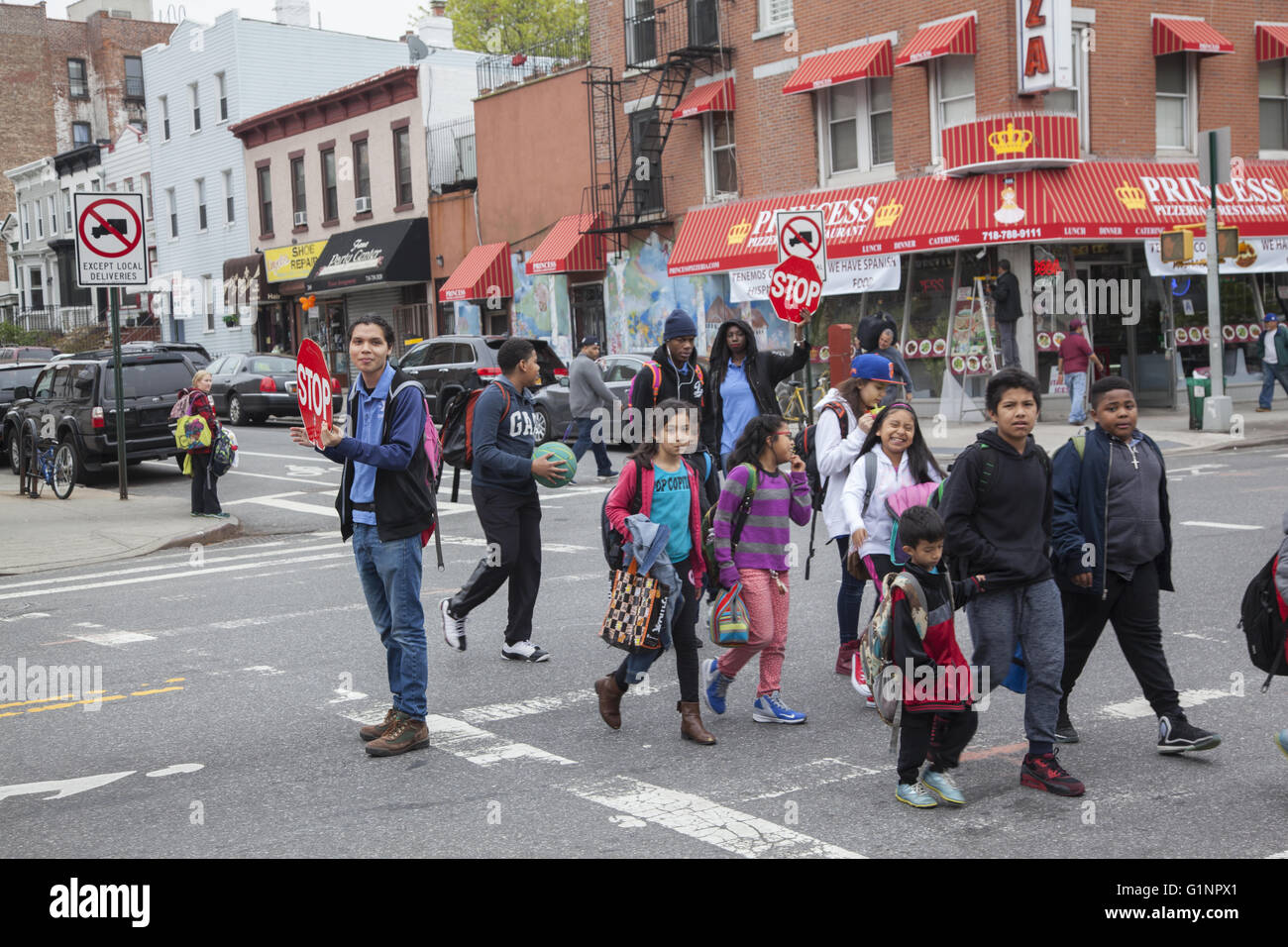 Gli insegnanti utilizzano segni di arresto per il traffico come scuola i bambini in un itinerario attraversa una grande Street in Brooklyn, New York. Foto Stock