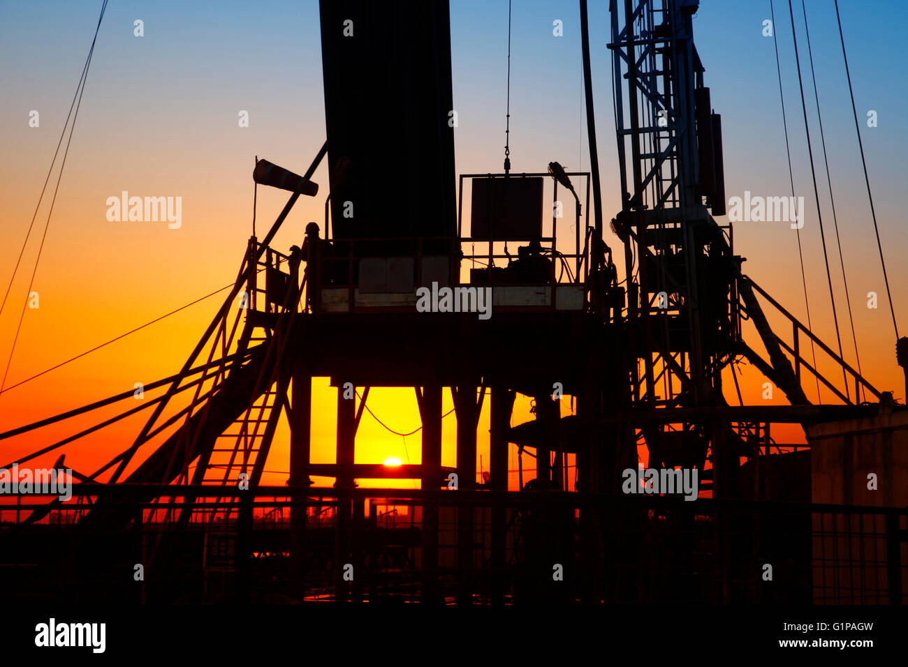 La sera del giacimento petrolifero, unità di pompaggio e la silhouette di oilfield derrick Foto Stock