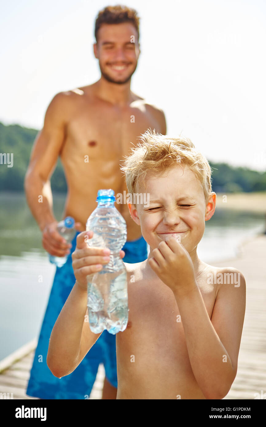 Padre e figlio la spruzzatura di ogni altra acqua con una bottiglia di acqua e divertirsi Foto Stock