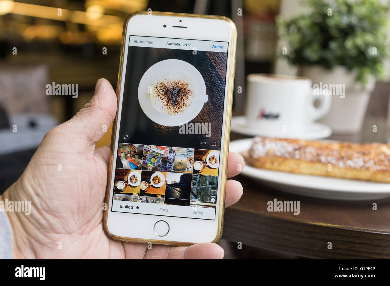 Berlino, Germania - 17 Maggio 2016: l'uomo mediante la riprogettazione di Instagram piattaforma su un iPhone bianco 6 Plus. Foto Stock