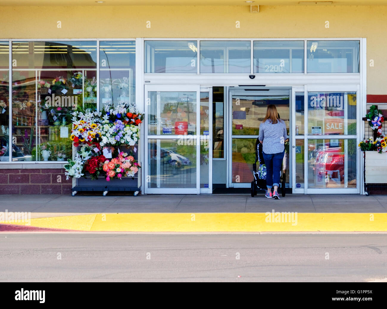 Una donna caucasica ruote il suo bambino attraverso la porta di un Michaels store sul Memorial road nel nord Oklahoma City, Oklahoma, Stati Uniti d'America. Foto Stock