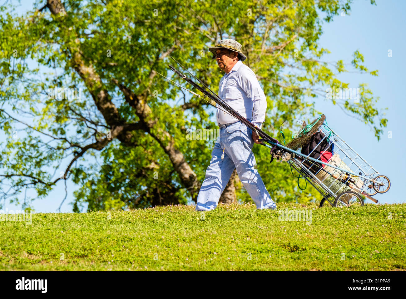 Un anziano uomo caucasico cale i suoi attrezzi da pesca in preparazione per andare a pescare. Oklahoma, Stati Uniti d'America. Foto Stock