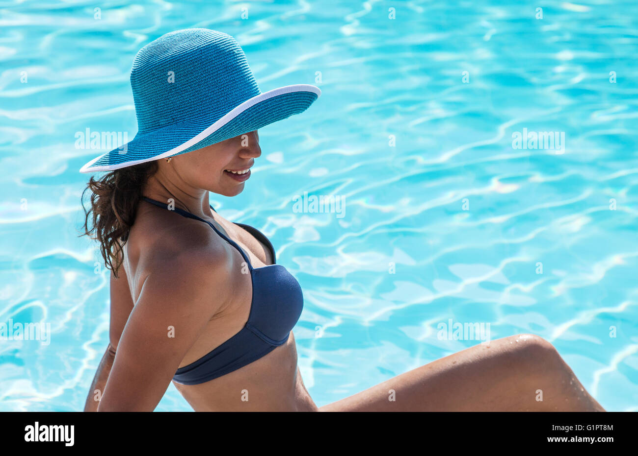 Donna seduta sul bordo della piscina. Foto Stock