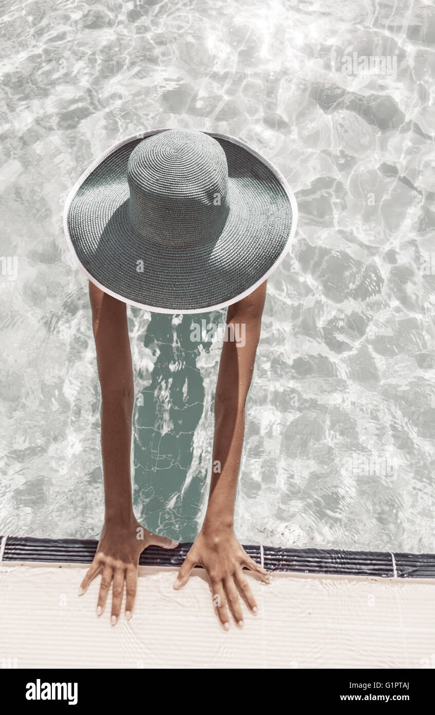 La donna nel cappello per il sole in piscina. Vista dall'alto. In stile vintage. Foto Stock