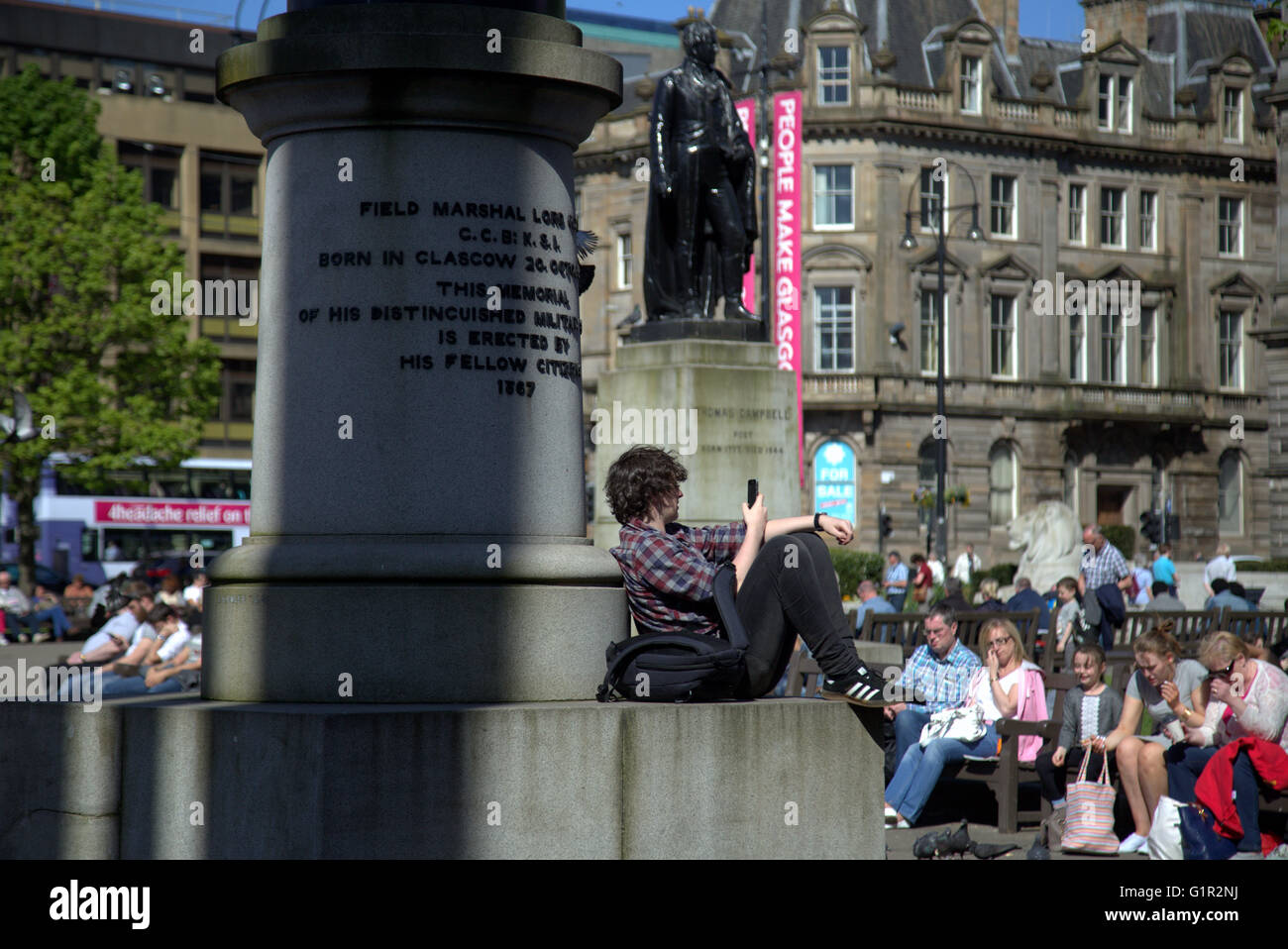 Giornata soleggiata con ragazzo su telefono George Square,Glasgow, Scotland, Regno Unito . Foto Stock