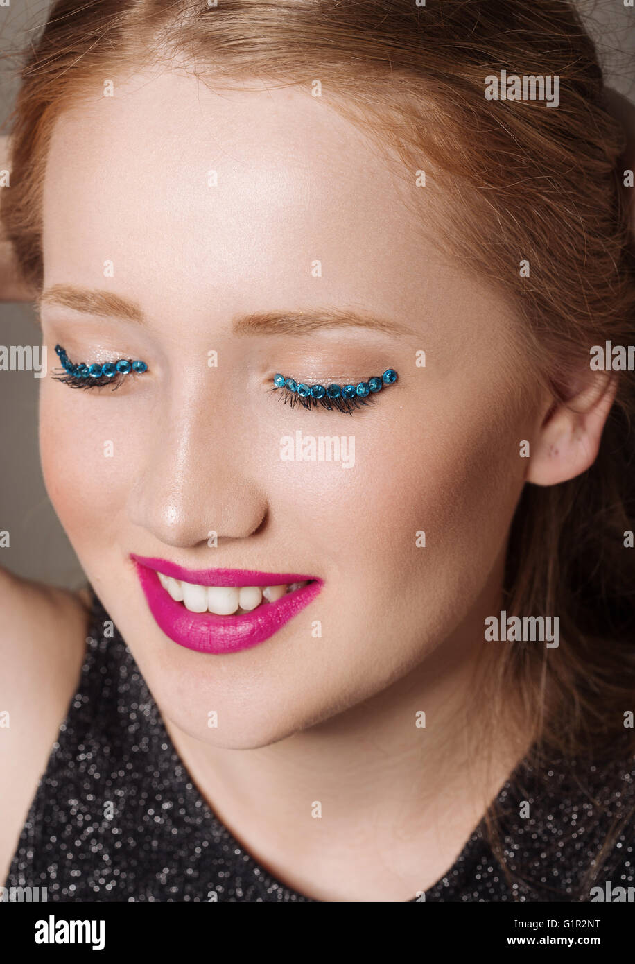 Ritratto di una giovane donna in studio con glittery trucco sorridente Foto Stock