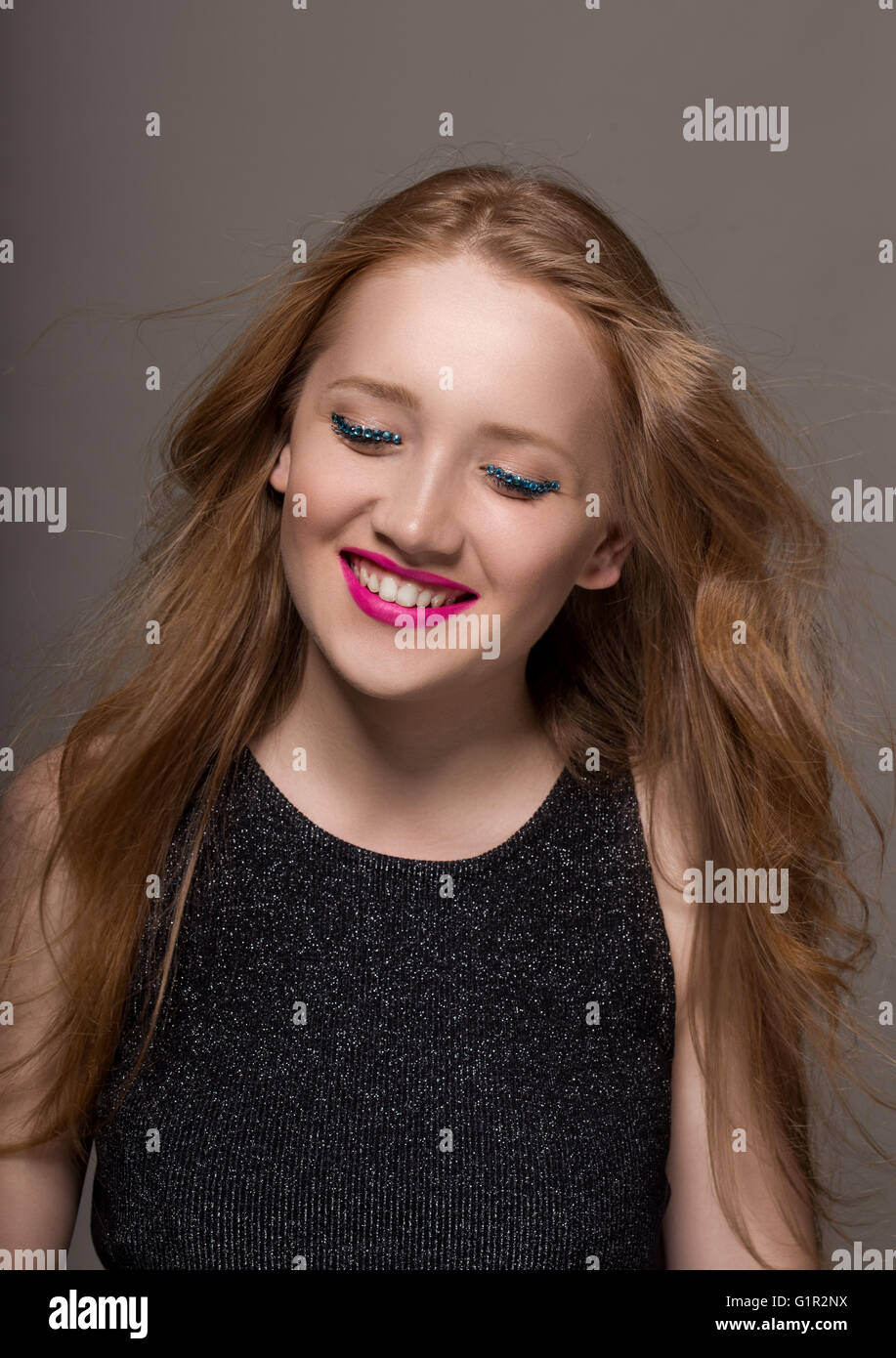 Ritratto di una giovane donna in studio con glittery trucco sorridente Foto Stock