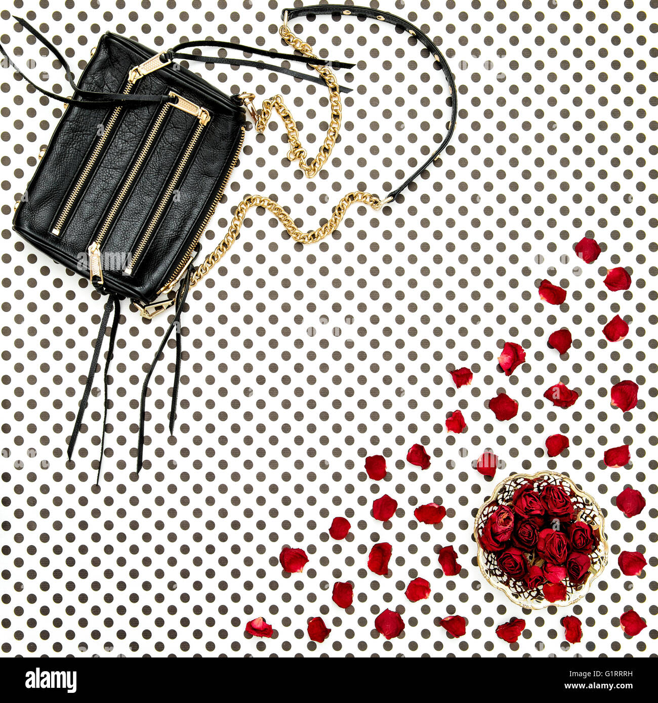 Moda lay piatto. Nera borsa in pelle e red rose fiori. Polka Dot sfondo Foto Stock