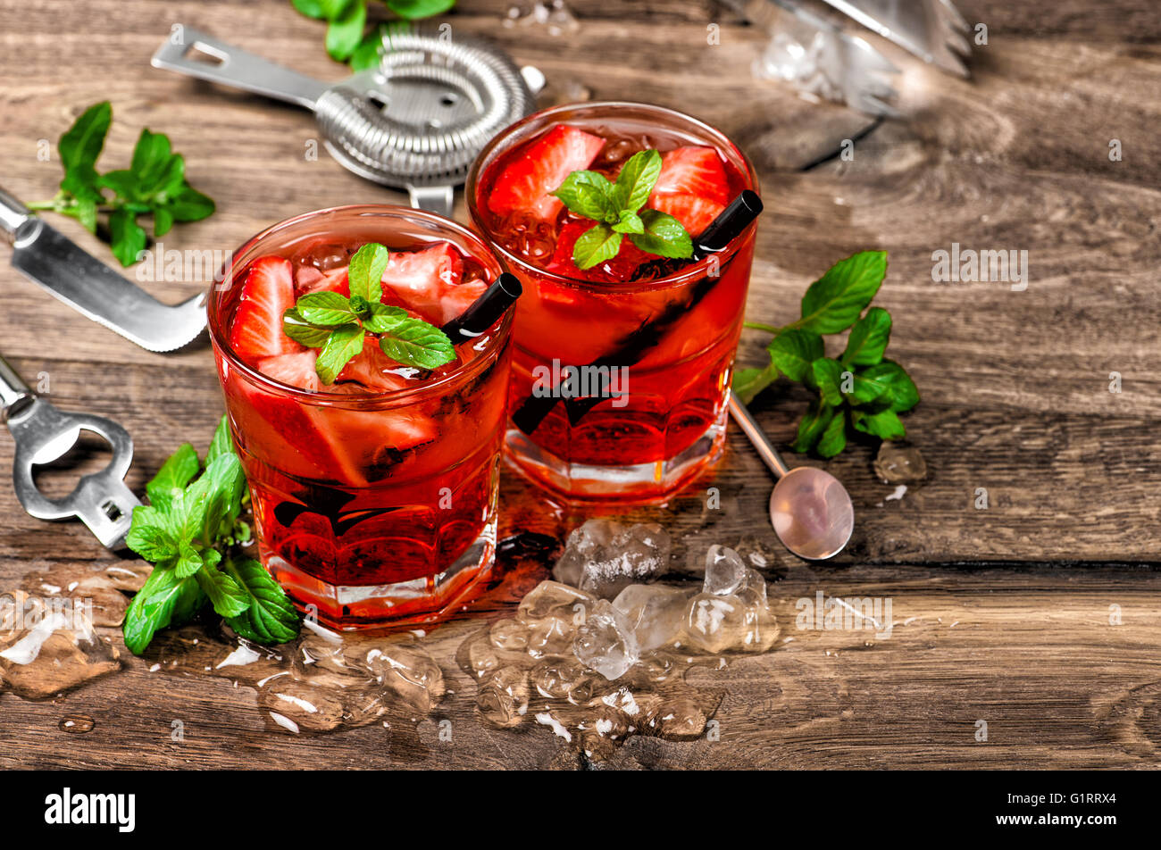 Red cocktail con ghiaccio, foglie di menta e fragola. Bevande alcoliche e non alcoliche rendendo gli strumenti della barra Foto Stock