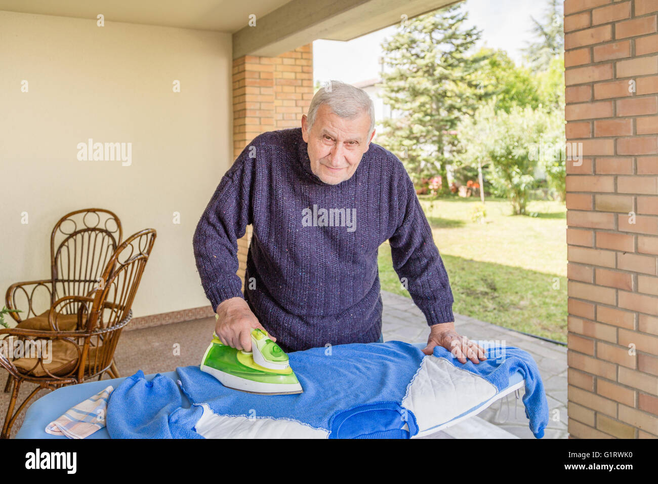 La stiratura Senior nel patio della sua casa Foto Stock