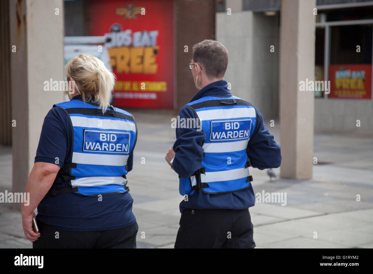 Consiglio BID Wardens Central Business District  due Bid Wardens, uomo e donna che indossano tavoli bianchi e blu hi-vis pattugliano le strade di Blackpool, Lancashire, Regno Unito Foto Stock