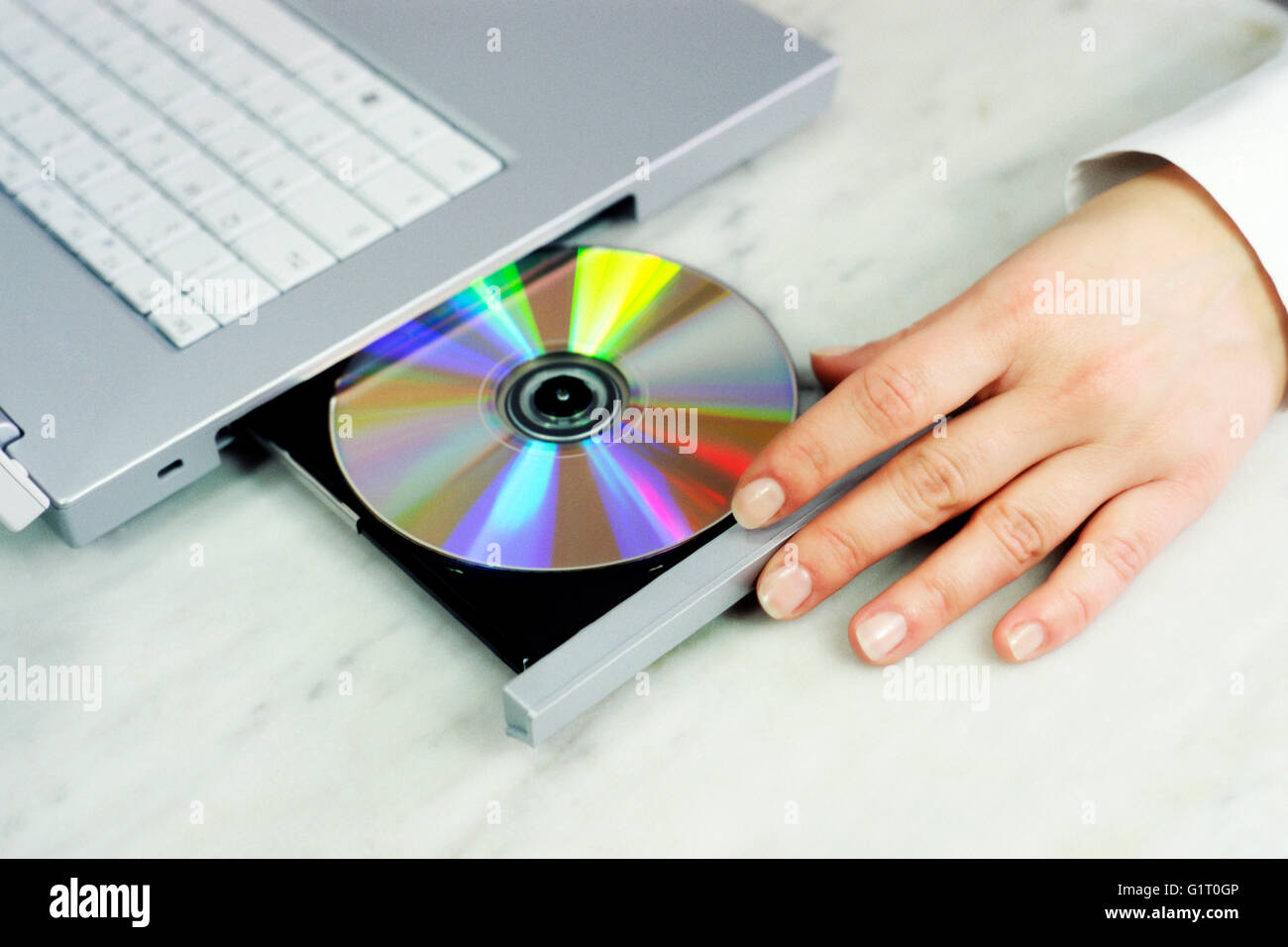 Donna mettendo il CD-ROM nel computer portatile Foto Stock