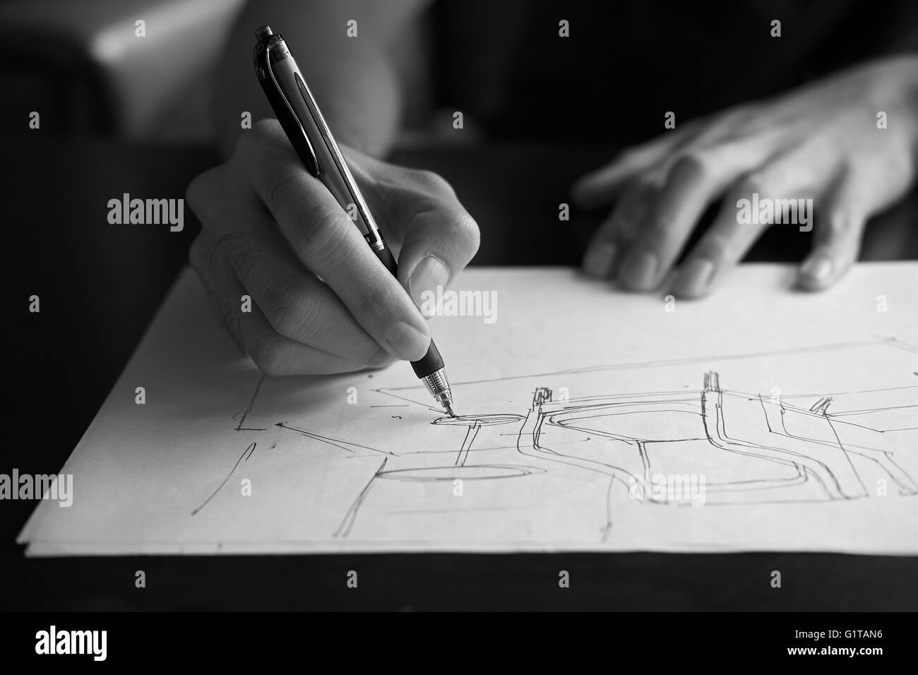 Mano di designer con la sua penna, progettando e delineando la sua idea su sketchbook in monocromia Foto Stock