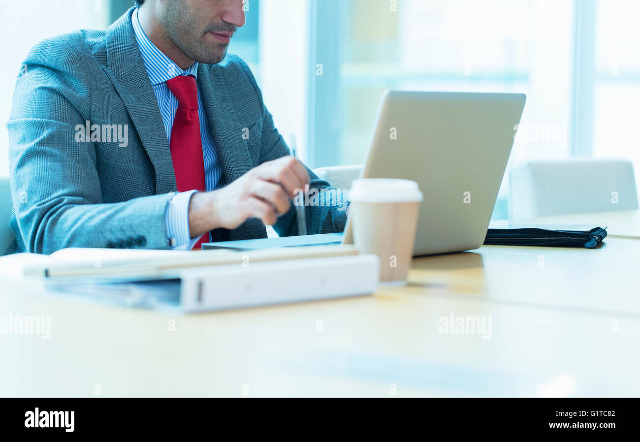 Imprenditore focalizzato lavora al computer portatile in sala conferenze Foto Stock