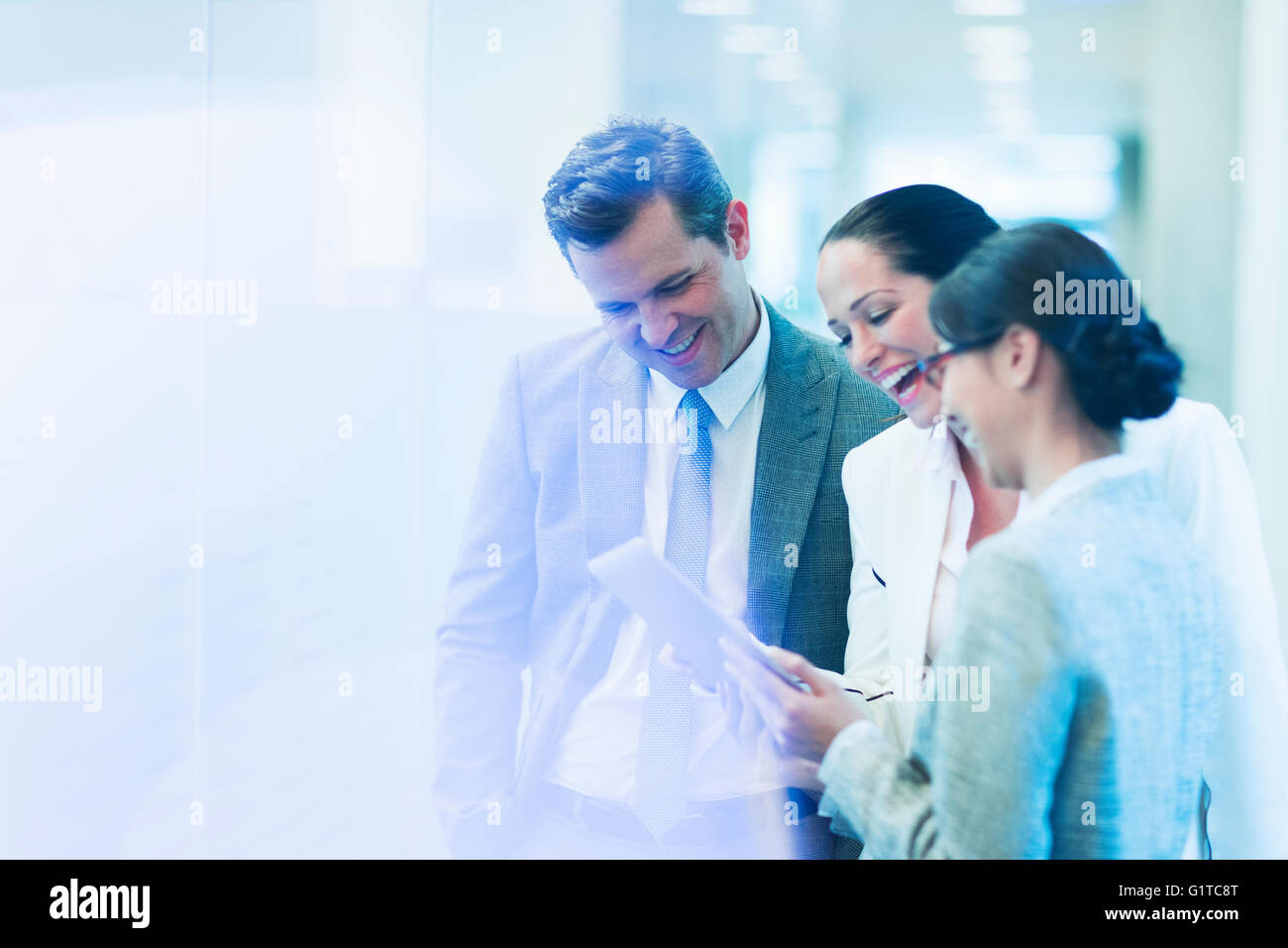 La gente di affari con tavoletta digitale ridendo nel corridoio di office Foto Stock