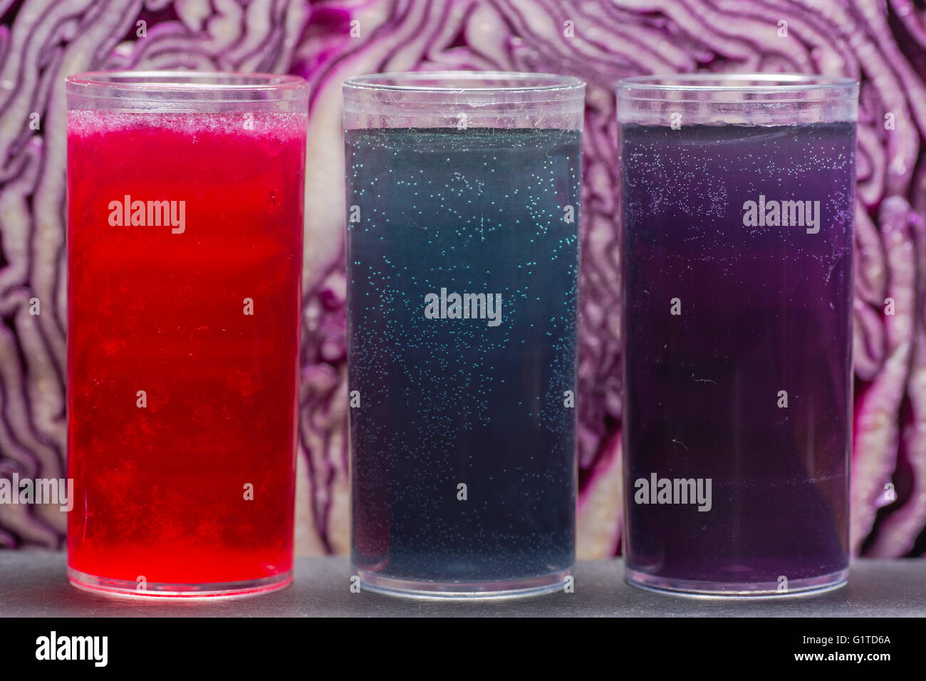 Cavolo rosso indicatore di pH soluzione. Acida succo di limone (rosso), alcali bicarbonato di sodio (blu) e acqua neutra (viola) Foto Stock