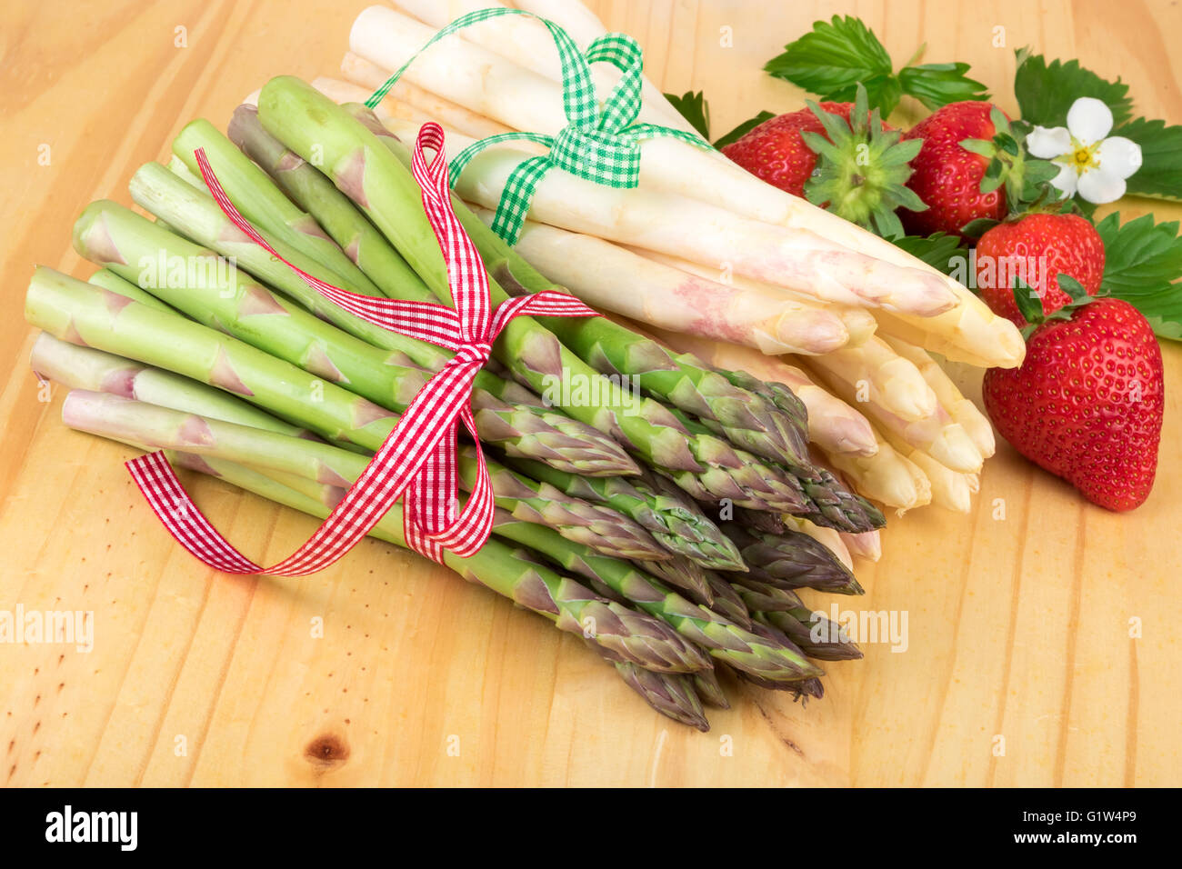 Verde asparagi bianchi con fragole fresche su legno luminoso. Alimenti vegani e vegetariani e cucina salutare concetto. Foto Stock