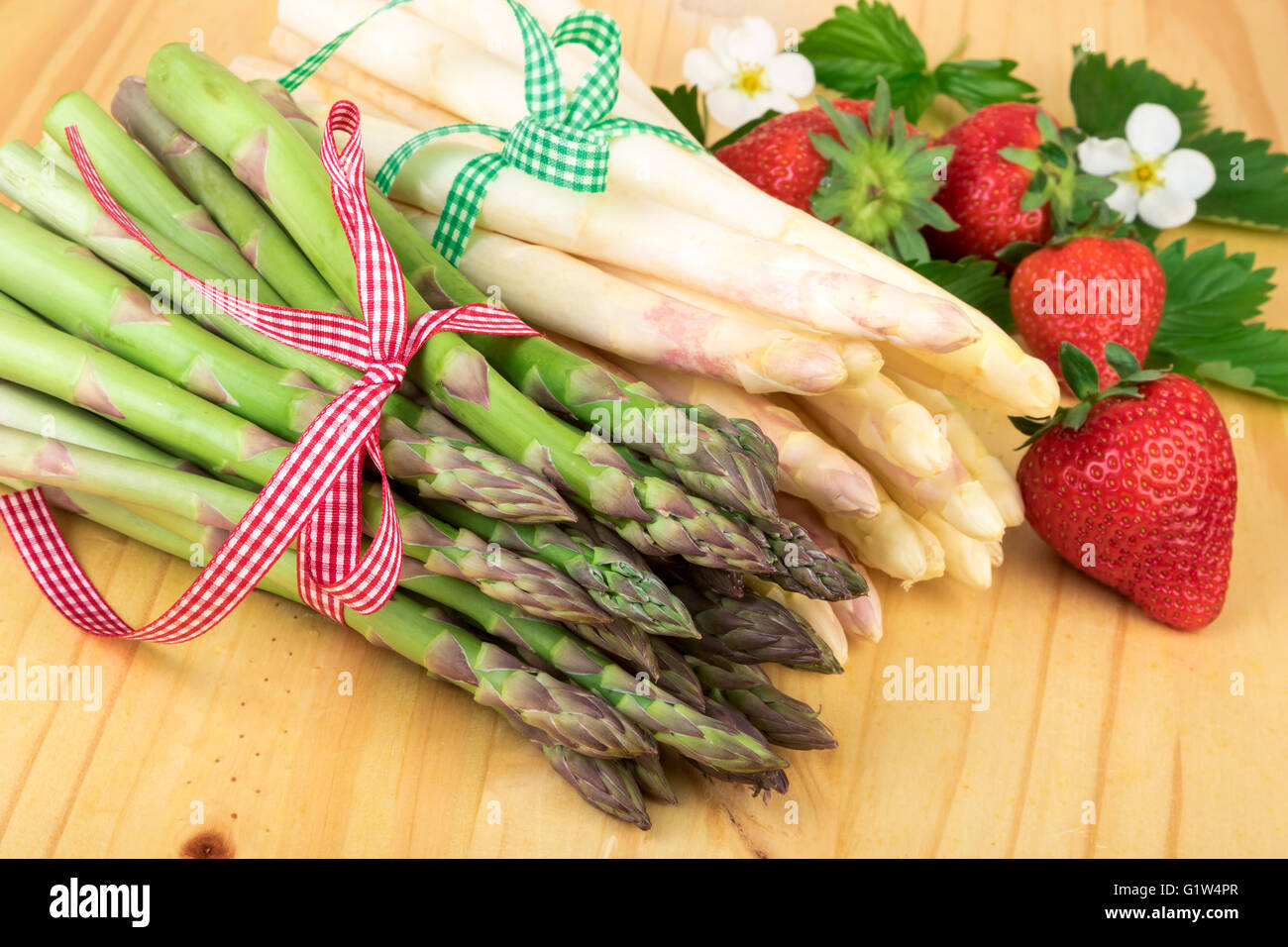 Asparagi freschi con fragole su legno. Alimenti vegani e vegetariani e cucina salutare concetto. Foto Stock