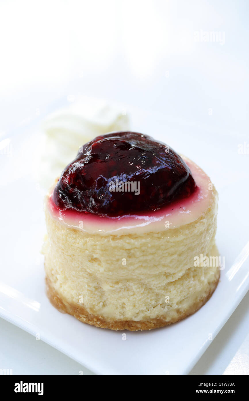 Mini cheesecake con lampone smalto sulla cima contro uno sfondo bianco Foto Stock