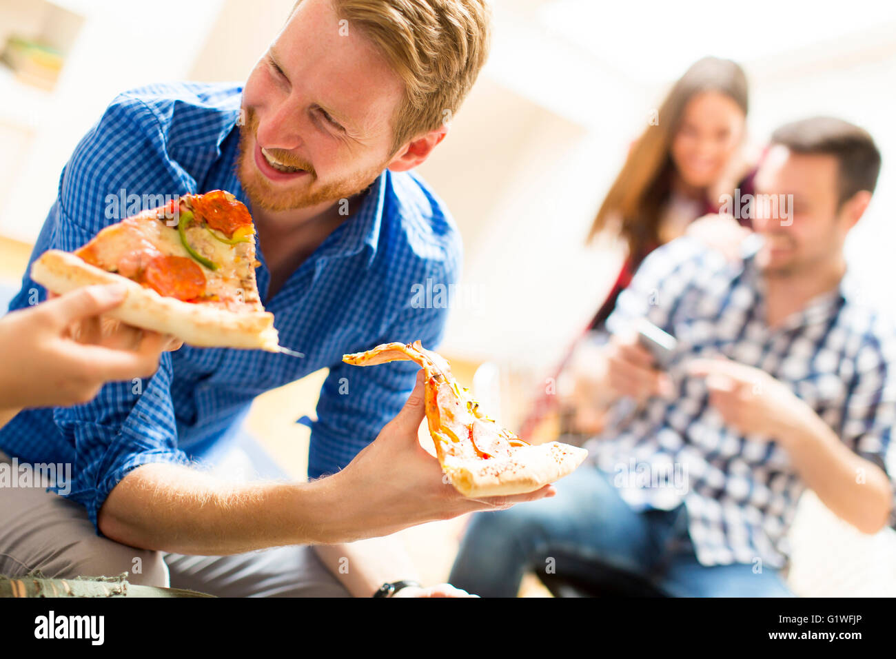 Uomo di mangiare la pizza con gli amici a casa Foto Stock