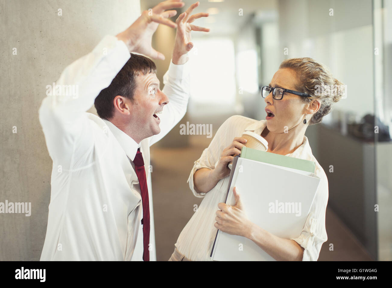 Imprenditore rendendo ululano gesto a terrorizzato imprenditrice Foto Stock