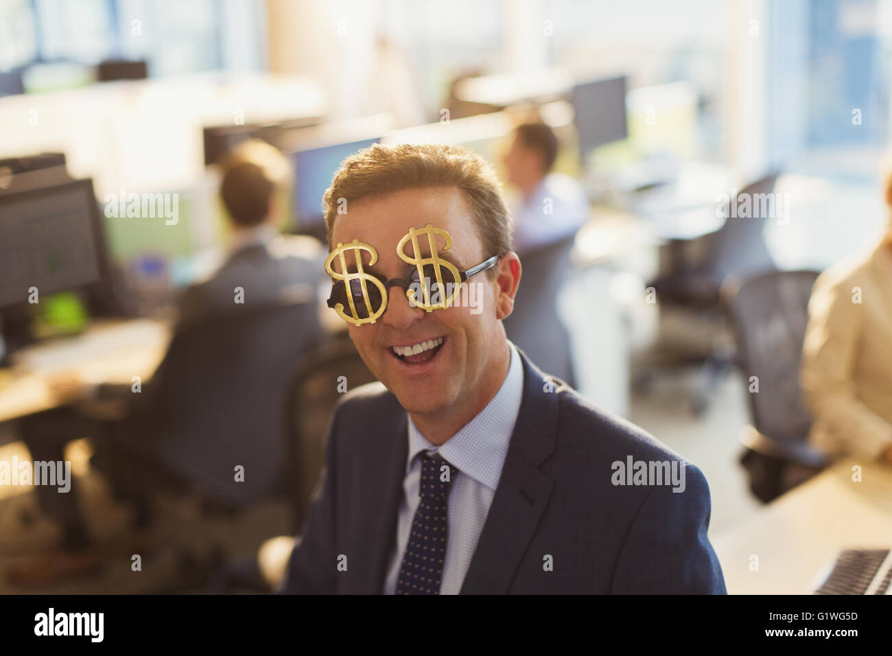 Ritratto di imprenditore sorridente indossando il simbolo del dollaro degli occhiali da sole in ufficio Foto Stock